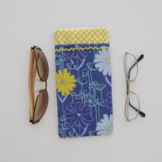 "This double pocket sleeve or case is a great organizer for 2 pairs of glasses. This case is made up in a blue, aqua, purple and yellow floral design cotton print fabric with a contrast yellow polka dot fabric. There is a purple cotton fabric lining. The main pocket will accommodate your sun glasses or eye glasses and the outside pocket is an easy slip in for your readers or a second pair of glasses. The pockets are also a designed to fit your cell phone and one pair of glasses, should you choos Blue Rectangular Case For Everyday Use, Blue Rectangular Case For Personal Use, Blue Cases With Pen Holders For Daily Use, Blue Cases With Pen Holders, Yellow Polka Dot, Dot Fabric, Eye Wear, Polka Dot Fabric, Glass Case