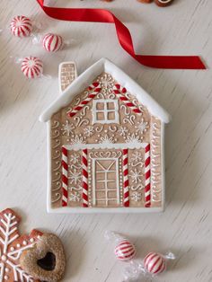 a gingerbread house is decorated with icing and candy canes on a table