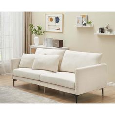 a white couch sitting on top of a hard wood floor next to a table and window