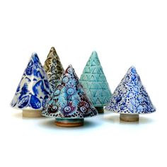 five small ceramic trees are lined up against a white background