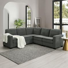 a living room with a gray sectional couch and white rugs on the hardwood floor