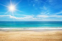 the sun shines brightly over an empty beach with blue water and white clouds in the background