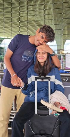 two people standing next to each other with luggage in front of them and one person covering his eyes