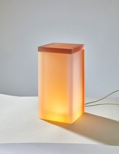 a light that is sitting on top of a table next to a white wall and floor