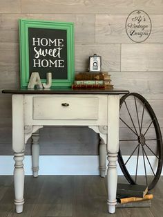 a white table with a green frame and some books on it next to a wheel