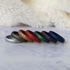 five different colored rings sitting on top of a white table next to a teddy bear