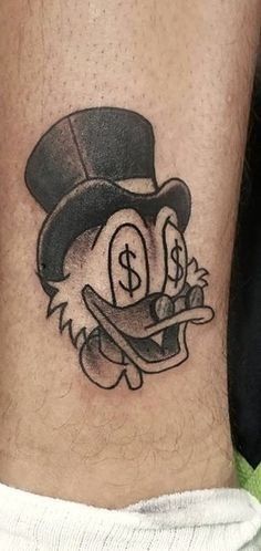 a tattoo on the leg of a person with a hat and dollar sign in it