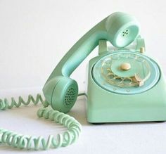 an old - fashioned green phone sits on a white surface