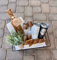 a basket filled with coffee cups sitting on top of a brick floor next to a potted plant