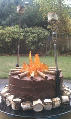 a chocolate cake sitting on top of a plate covered in frosting and wood logs