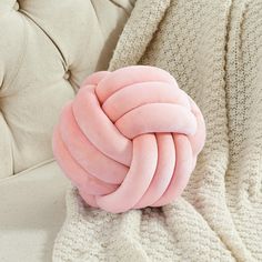 a pink ball of yarn sitting on top of a white couch next to a blanket