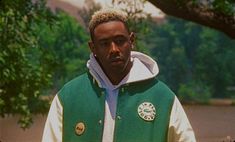 a man standing in front of a tree wearing a green and white jacket