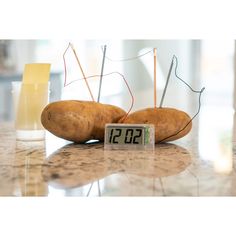 two potatoes sitting on top of a counter next to a clock with thermometer