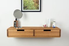 a wooden shelf with two drawers and a mirror on it next to a white wall