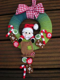 a knitted christmas wreath with a santa clause on top and candy canes hanging from it