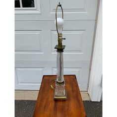 an old fashioned lamp sitting on top of a wooden table in front of a door