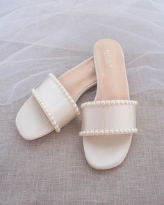 a pair of white shoes with pearls on the toes and heel are sitting on a bed