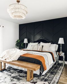 a bedroom with a large bed and black headboard on the wall next to a wooden bench