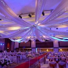 a banquet hall decorated with white and red linens, draping and flowers