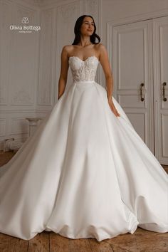 a woman in a white wedding dress standing on a wooden floor