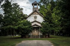 an old church with a steeple surrounded by trees