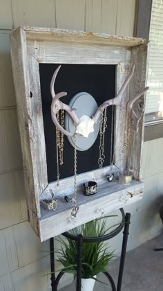 an old wooden frame with jewelry hanging from it's sides and a deer skull on the inside