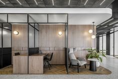 an office with wooden paneling and glass partitions to divide the space between two desks