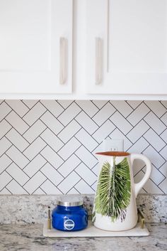 a coffee pot sitting on top of a counter next to a blue container and white cabinets