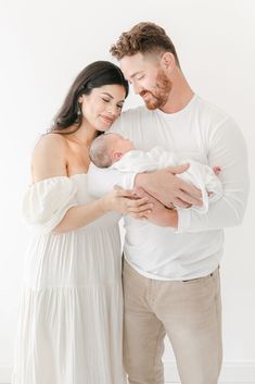 a man and woman holding a baby in their arms