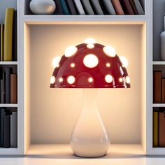 a red and white lamp sitting on top of a table next to a book shelf