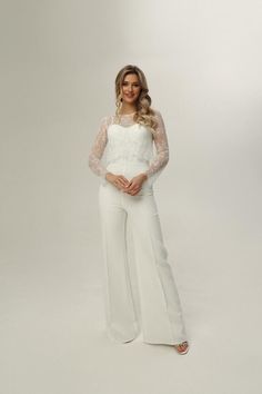 a woman is posing for a photo in white pants and a lace top with her hands on her hips