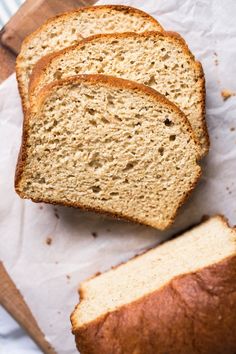 three slices of bread sitting on top of a cutting board next to a loaf of bread