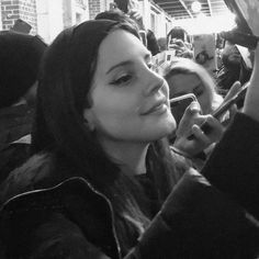 a black and white photo of a woman talking on her cell phone at a sporting event