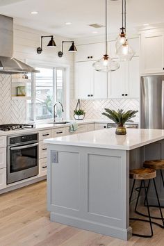 a kitchen with white cabinets and an island in front of a stove top oven next to two stools