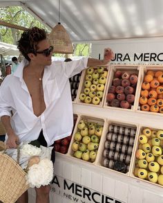 a woman standing in front of a display of fruit