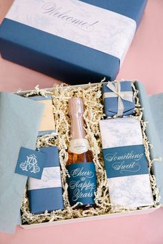 a bottle of wine in a gift box next to two blue boxes with white writing on them