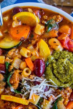 a white bowl filled with pasta, vegetables and pesto on top of a blue towel