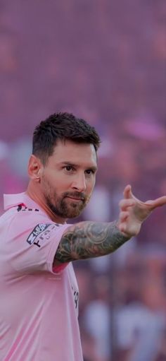 a man with tattoos on his arm pointing to the side while wearing a pink shirt