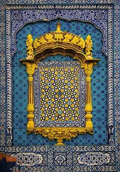 an ornate blue and yellow wall with gold decorations