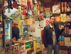 two men standing in front of a store filled with sodas and candy bars,