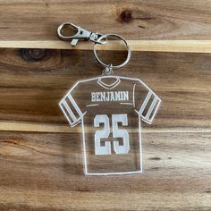 an acrylic keychain with the number 25 on it is hanging from a wooden surface