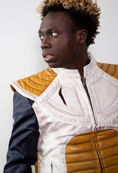 a young man wearing a leather vest and looking off to the side