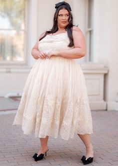 a woman in a white dress posing for the camera with her hands on her hips