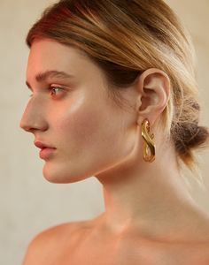 a woman wearing large gold earrings on her ear