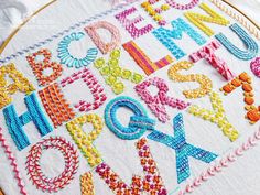 a close up of a cross stitch pattern on a piece of cloth with letters and numbers