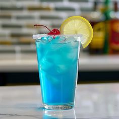 a blue drink with ice and a cherry on the rim, garnished with a slice of lemon