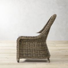 a wicker chair sitting on top of a wooden floor next to a white wall