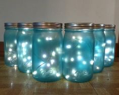 four blue mason jars with lights in them