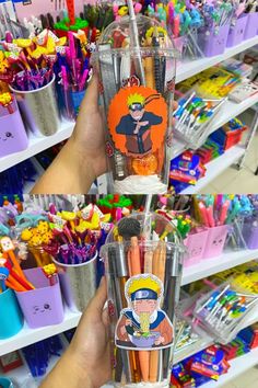 the person is holding up two cups with pencils in it and cartoon characters on them