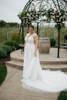 a woman standing in front of a gazebo wearing a white wedding dress and veil